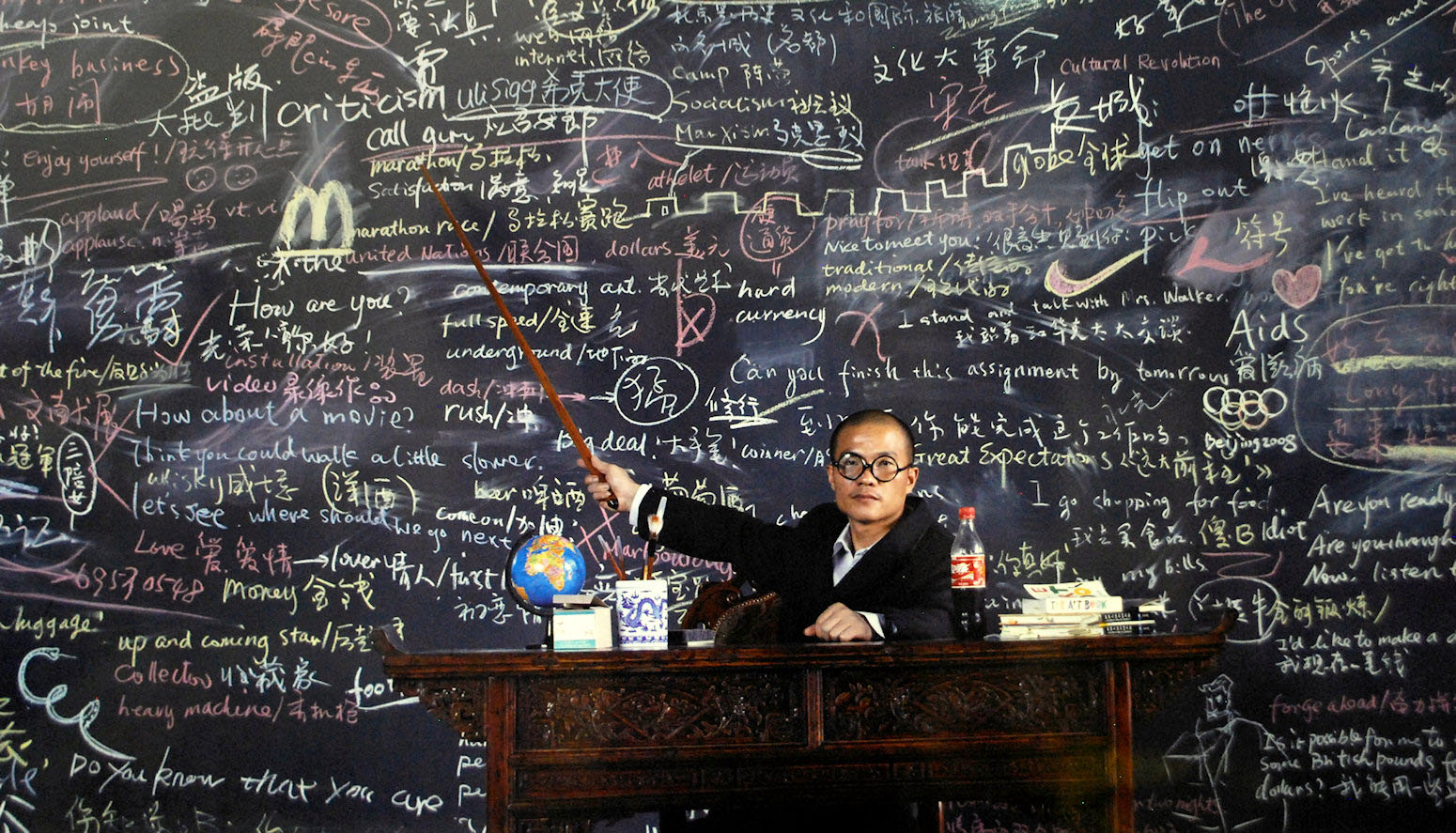Chalkboard full of writing, man pointing at it
