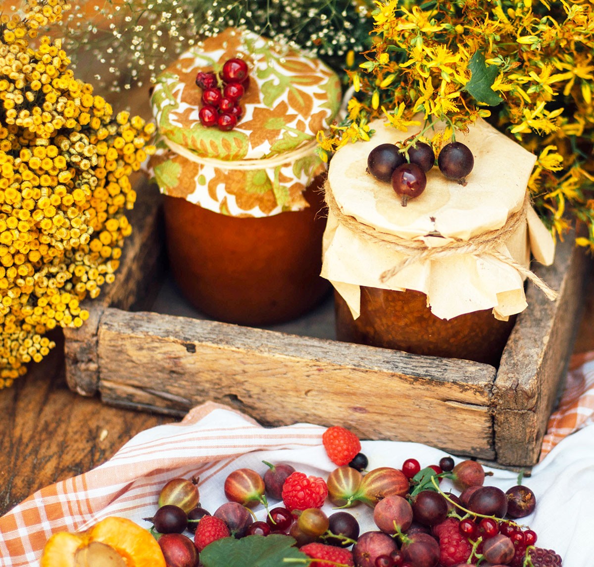 Delicious jars of jam in crate, surrounded by fresh fruit and fall foliage
