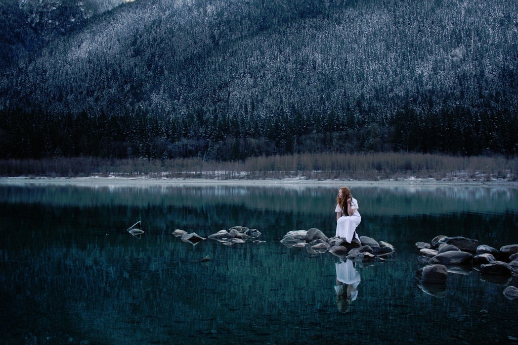 Girl in black and white photo at water's edge